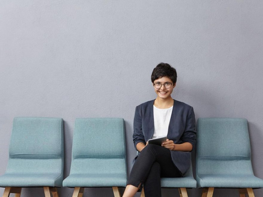 Woman seated with a tablet in a bank waiting area after booking an appointment